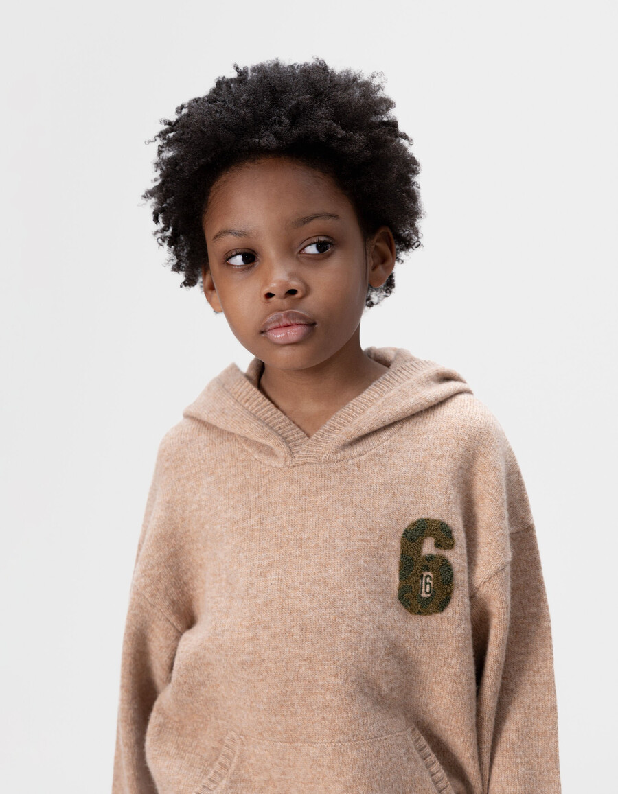 beige melierte strickkapuze für jungen mit nummernaufnäher