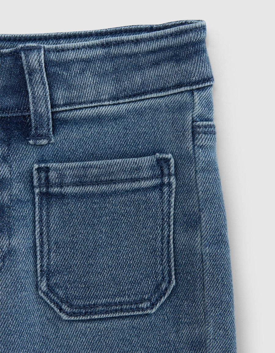 mädchen-jeans mit blauem schlag und aufgesetzten taschen